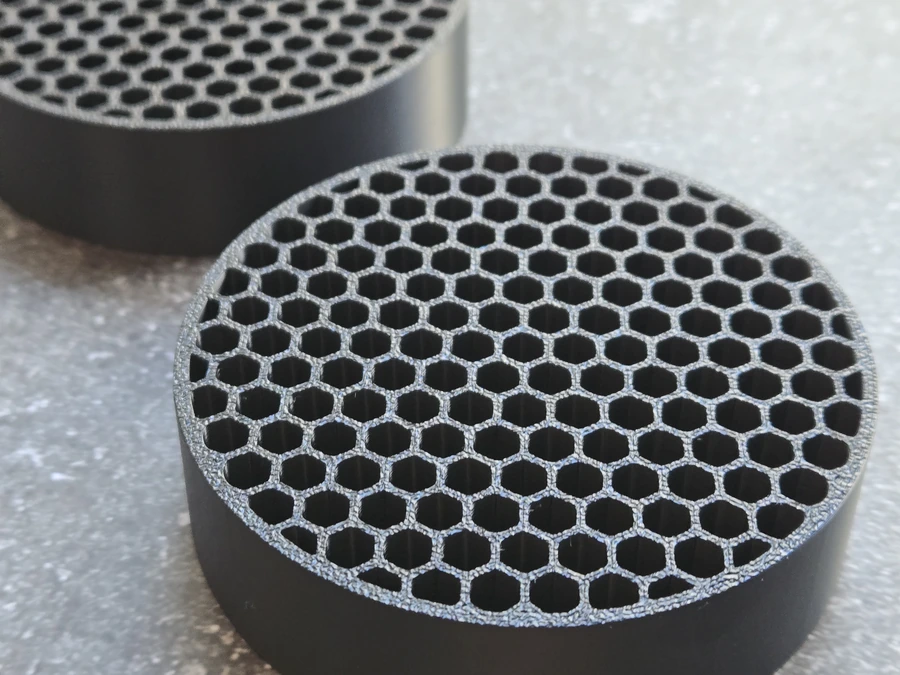 Two black ASA intake flow straighteners with honeycomb cells shown close up