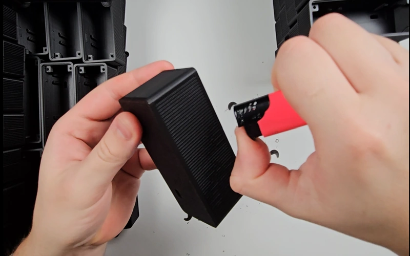 Flame finishing a 3D printed enclosure to remove fine PLA strings.