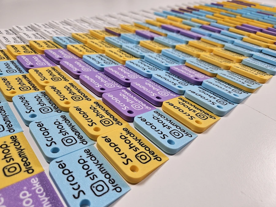 Large batch of pastel-coloured branded mini scrapers laid out in rows.